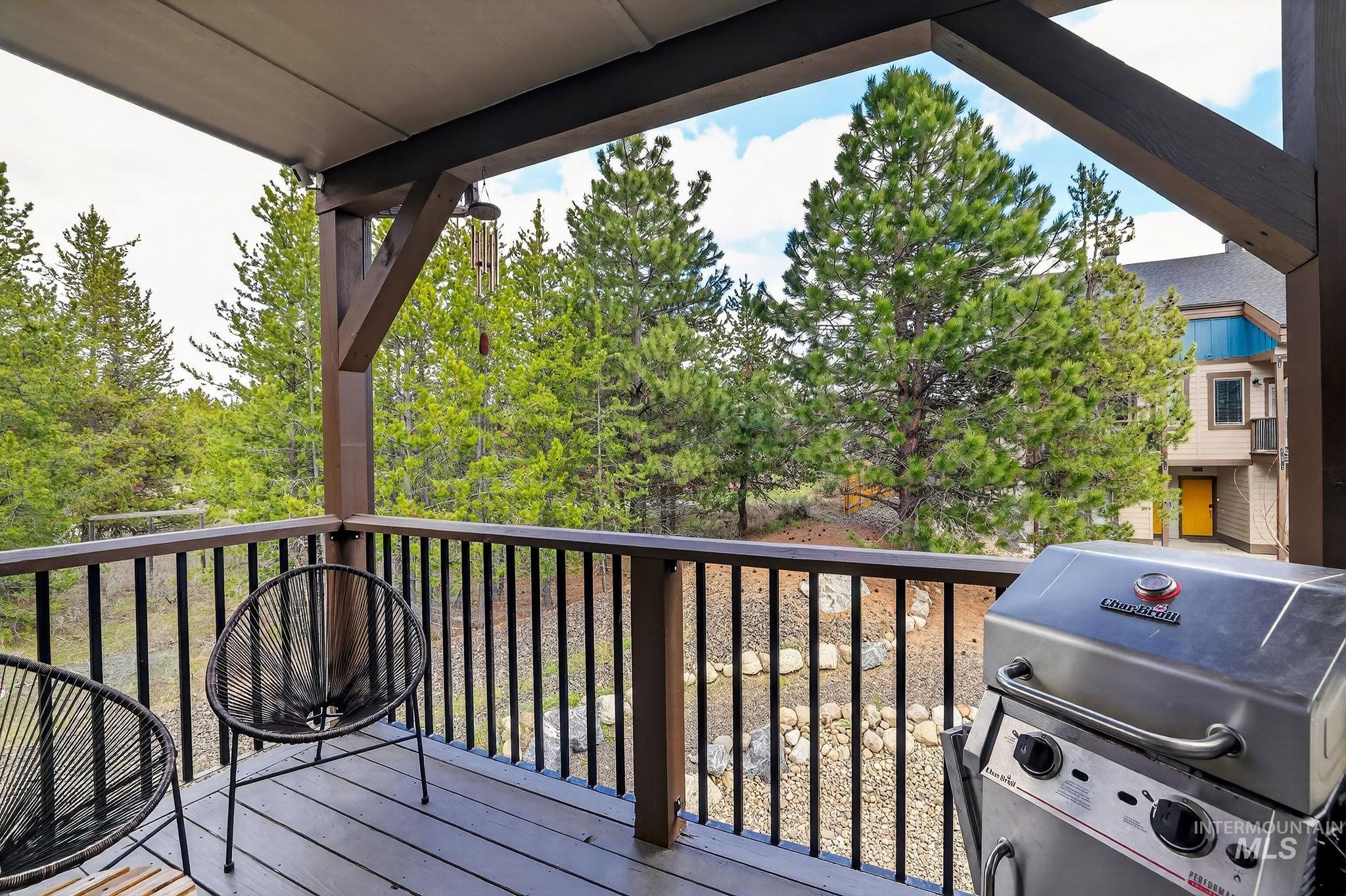 311 Broken Ridge Way McCall, ID 83638 - Photo 12 of 44 Covered outdoor deck with wood-finish flooring, dark wood railing, and surrounding evergreen trees