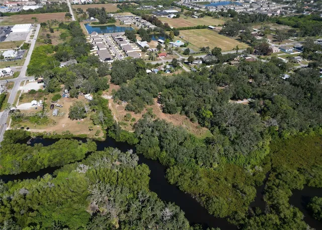 an aerial view of a residential houses with outdoor space and trees