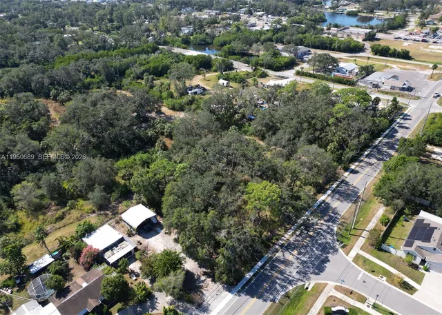 an aerial view of residential house with outdoor space and trees all around