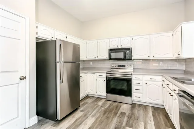 a kitchen with a refrigerator stove and white cabinets