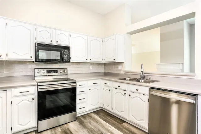 a kitchen with granite countertop white cabinets white stainless steel appliances and a sink