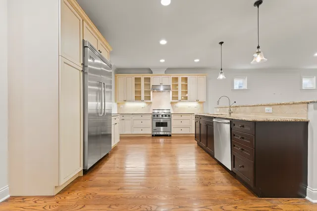 a large kitchen with stainless steel appliances granite countertop a sink a stove and a wooden floors