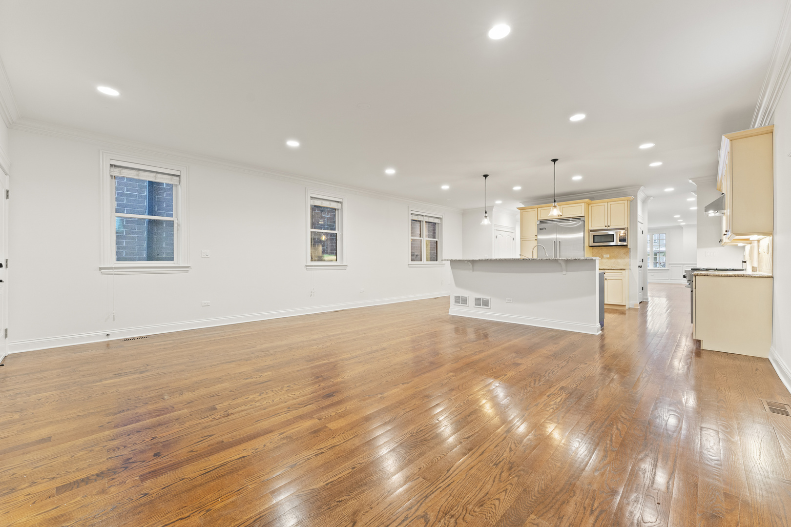 3716 North Kenmore Avenue, Unit 1 Chicago, IL 60613 - Photo 10 of 26 a view of an empty room with wooden floor and a kitchen