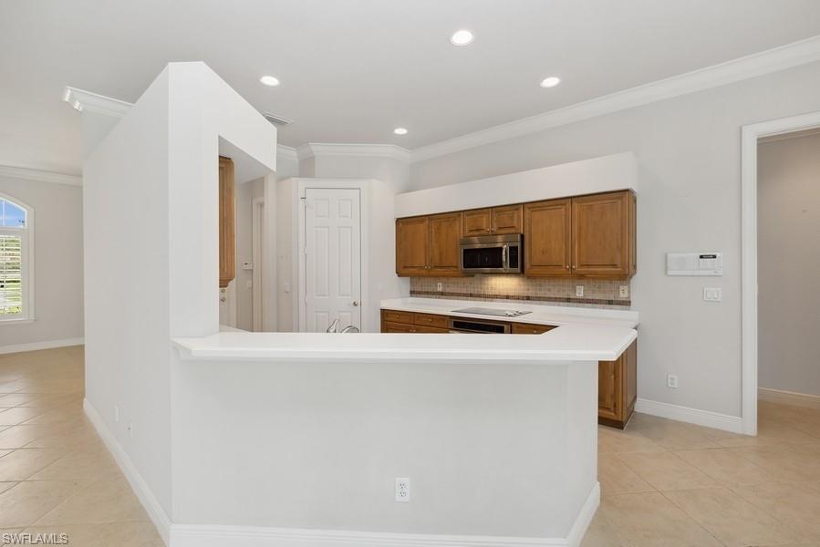 502 Cormorant Cove Naples, FL 34113 - Photo 7 of 25 a kitchen with stainless steel appliances a stove top oven a sink and a refrigerator