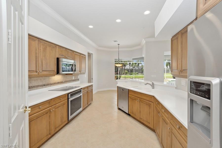502 Cormorant Cove Naples, FL 34113 - Photo 9 of 25 a large kitchen with stainless steel appliances granite countertop a stove and a sink