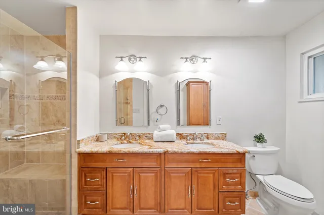 a bathroom with a granite countertop sink a toilet and a mirror
