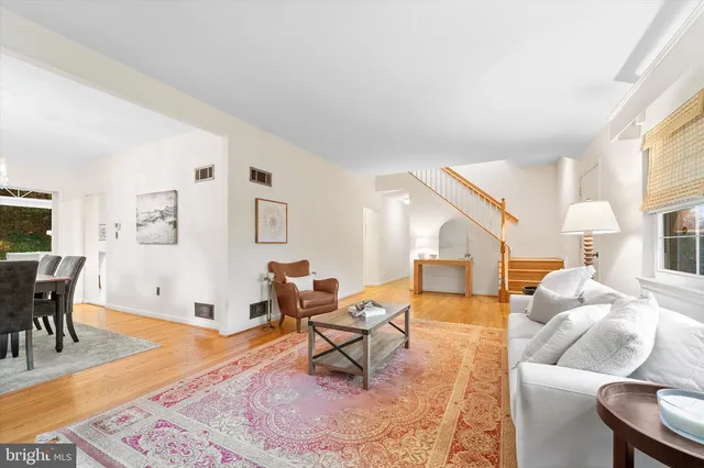 a living room with furniture and a dining table with wooden floor