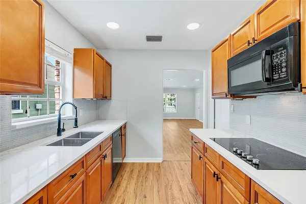 a kitchen with stainless steel appliances granite countertop a sink a stove a microwave cabinets and a wooden floor