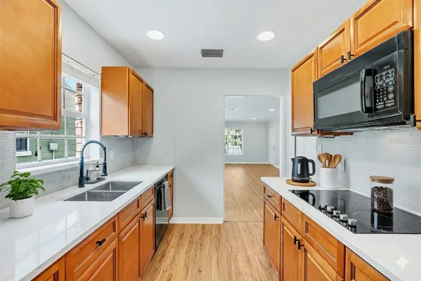a kitchen with stainless steel appliances granite countertop a sink a stove top oven a counter space and cabinets