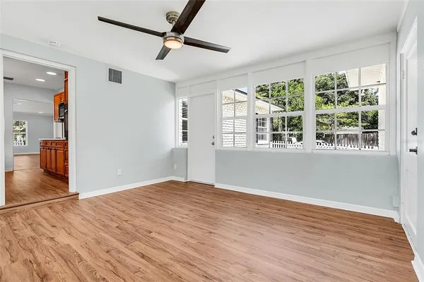 a view of empty room with wooden floor and fan