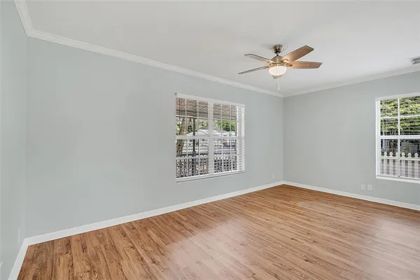 a view of an empty room with wooden floor and a window