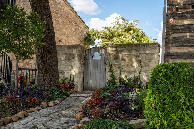 a stone house with a flower garden in front of it
