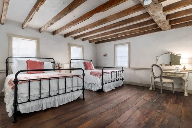 a bedroom with two beds and wooden floor