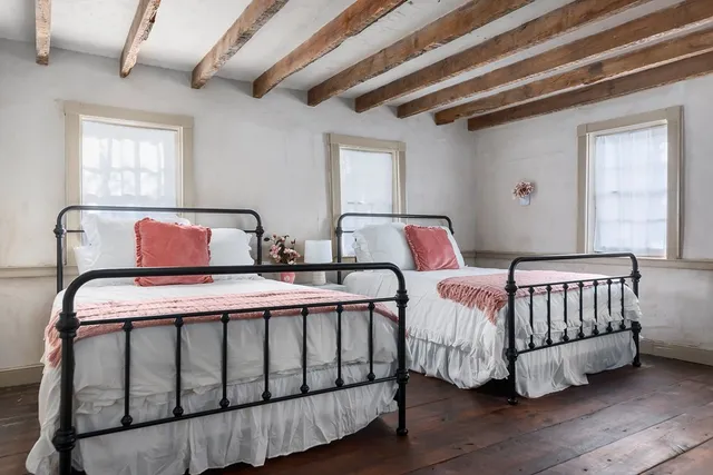 a bedroom with two beds and wooden floor