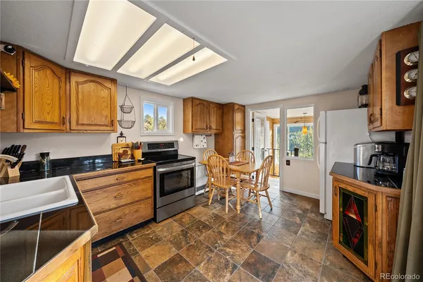 a kitchen with stainless steel appliances granite countertop a stove top oven a sink a dining table and chairs with wooden floor