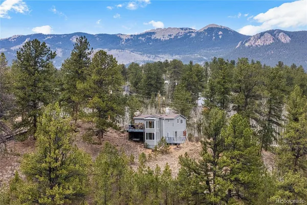a front view of a house with a yard and mountain view in back