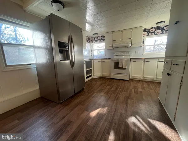 a kitchen with stainless steel appliances a refrigerator and a hard wood floor