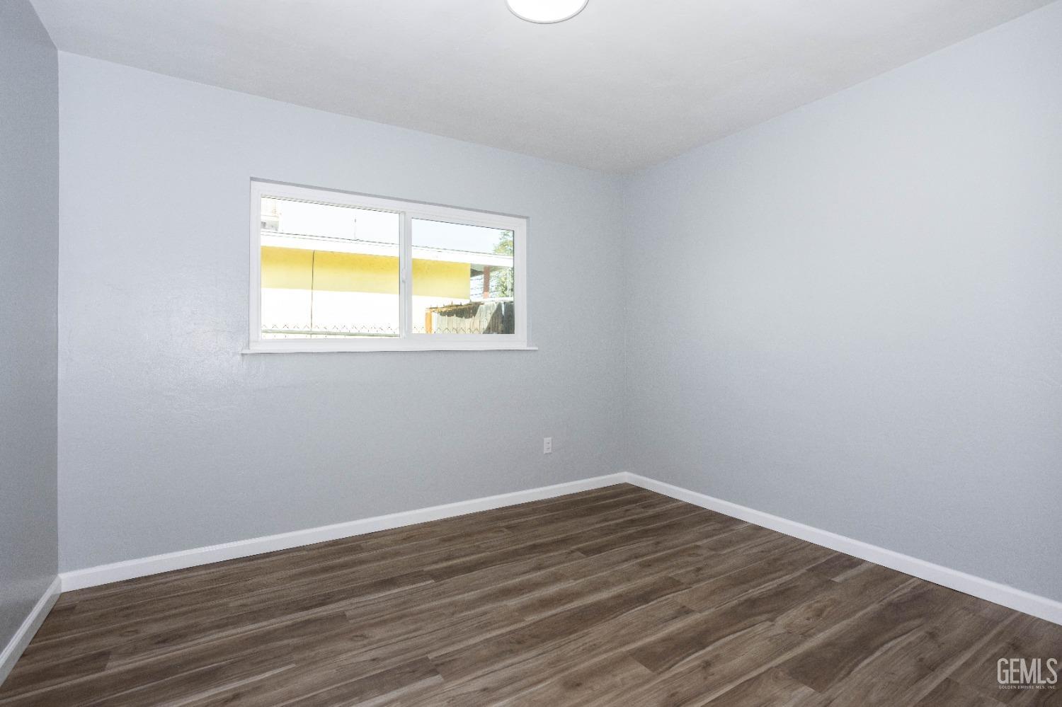 Undisclosed Address Shafter, CA 93263 - Photo 16 of 18 a view of an empty room with wooden floor and a window