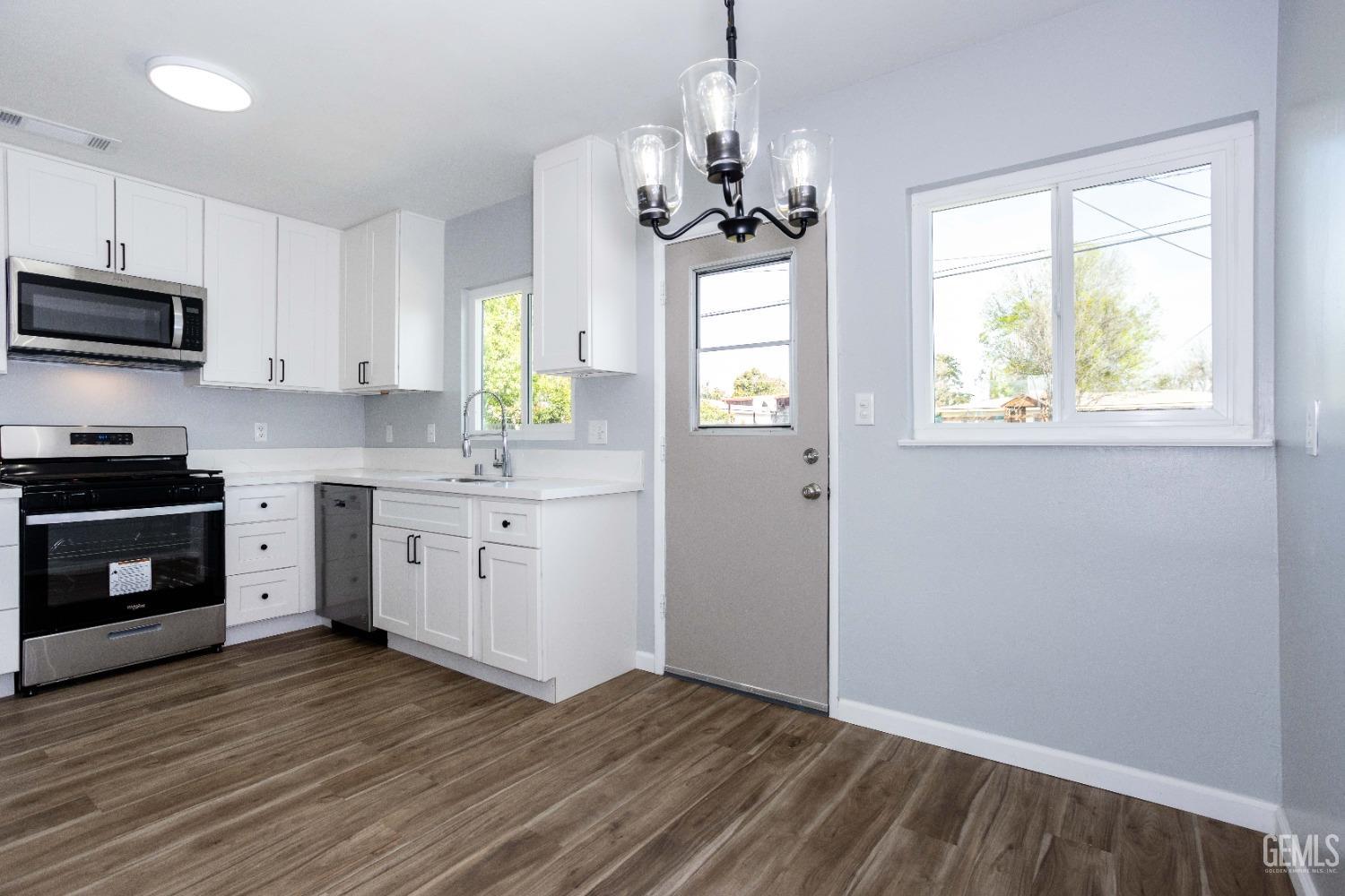 Undisclosed Address Shafter, CA 93263 - Photo 9 of 18 a kitchen with wooden floors and white cabinets