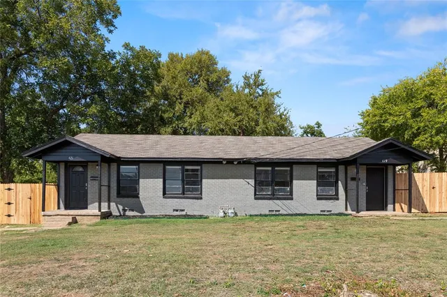 a front view of a house with a garden and tree