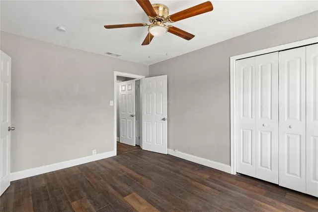 an empty room with wooden floor fan and windows