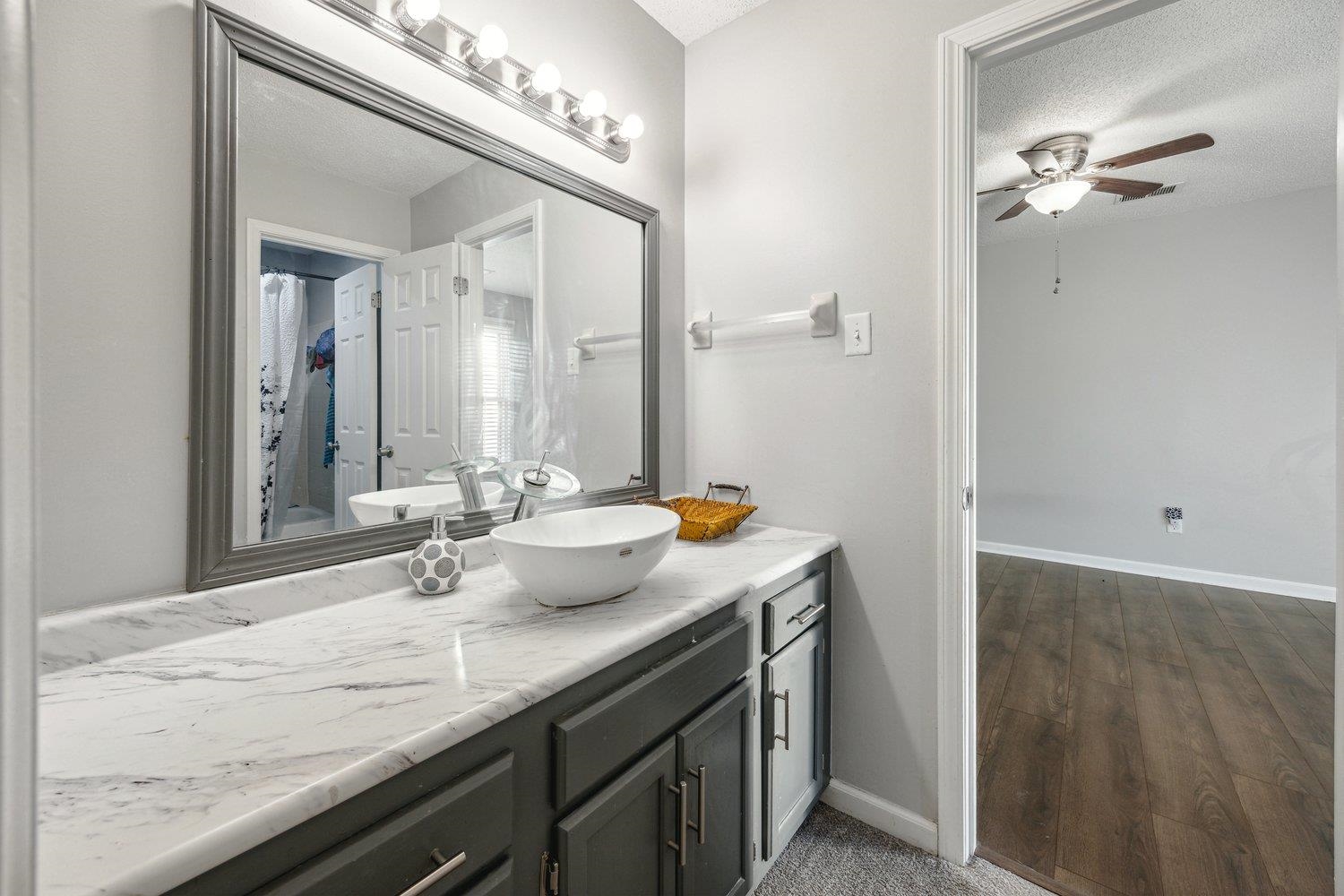8747 Walnut Grove Road Memphis, TN 38018 - Photo 17 of 20 a bathroom with a granite countertop sink and a mirror