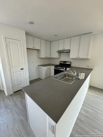 a kitchen with granite countertop a sink a stove and a wooden floors