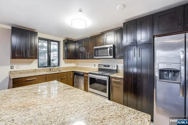 a kitchen with granite countertop stainless steel appliances and a refrigerator