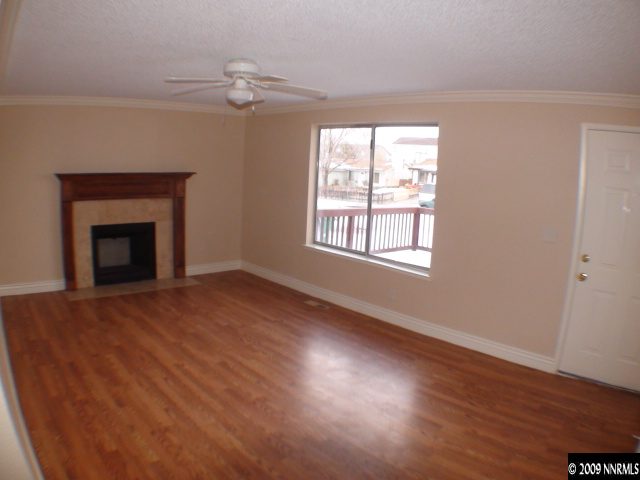13081 Exinite Drive Reno, NV 89506 - Photo 3 of 9 an empty room with wooden floor fireplace and windows