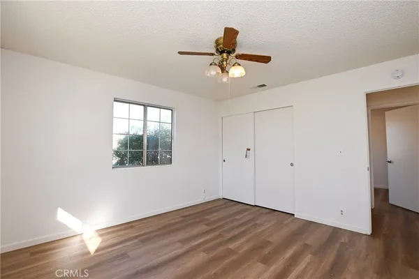 a view of empty room with wooden floor and fan