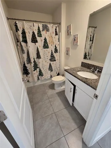 a bathroom with a granite countertop sink a toilet and shower curtain