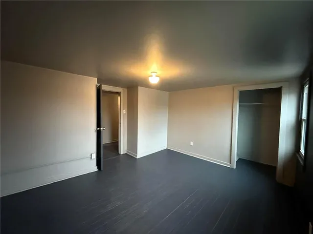 a view of an empty room with wooden floor and closet