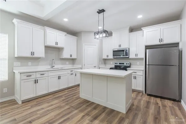 a kitchen with stainless steel appliances granite countertop a refrigerator a oven a white stove a sink dishwasher and a refrigerator with wooden floor