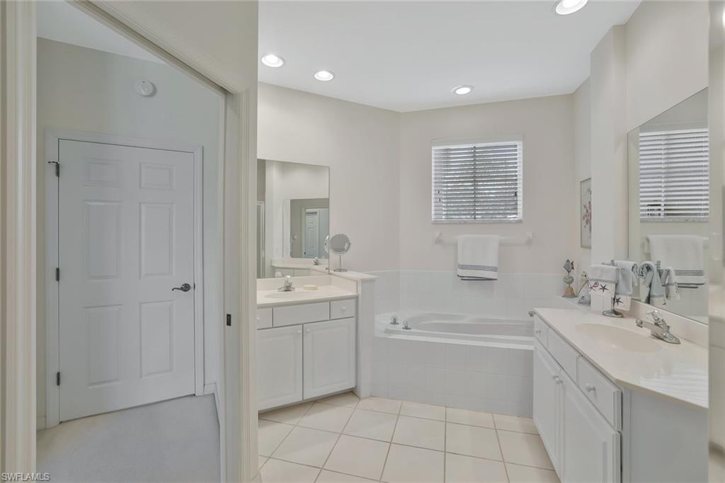 8457 Radcliffe Terrace, Unit 102 Naples, FL 34120 - Photo 17 of 33 Bathroom featuring two vanities, light tile patterned floors, a garden tub, and recessed lighting