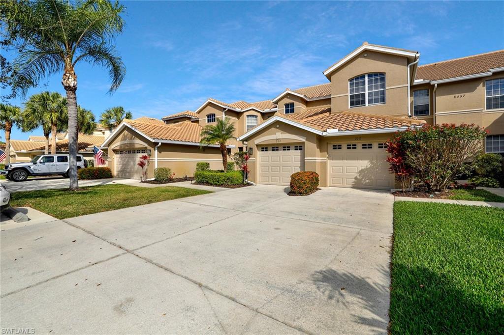 8457 Radcliffe Terrace, Unit 102 Naples, FL 34120 - Photo 2 of 33 Mediterranean / spanish home featuring stucco siding, concrete driveway, a front lawn, and a tiled roof