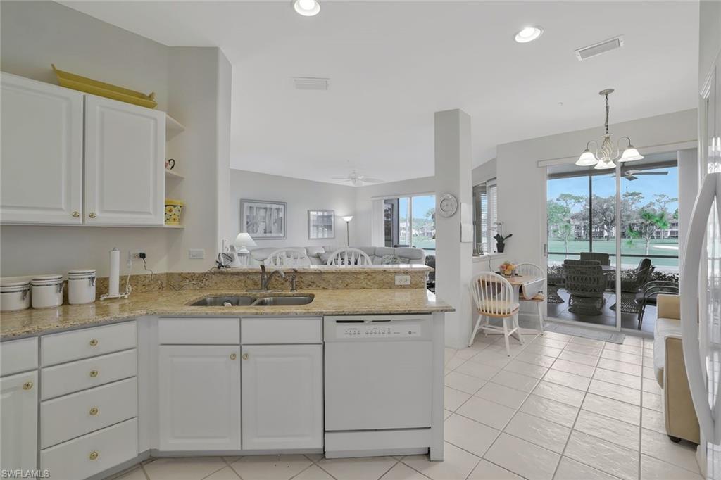 8457 Radcliffe Terrace, Unit 102 Naples, FL 34120 - Photo 33 of 33 Kitchen featuring light stone counters, open floor plan, white appliances, suspended lighting, and white cabinetry