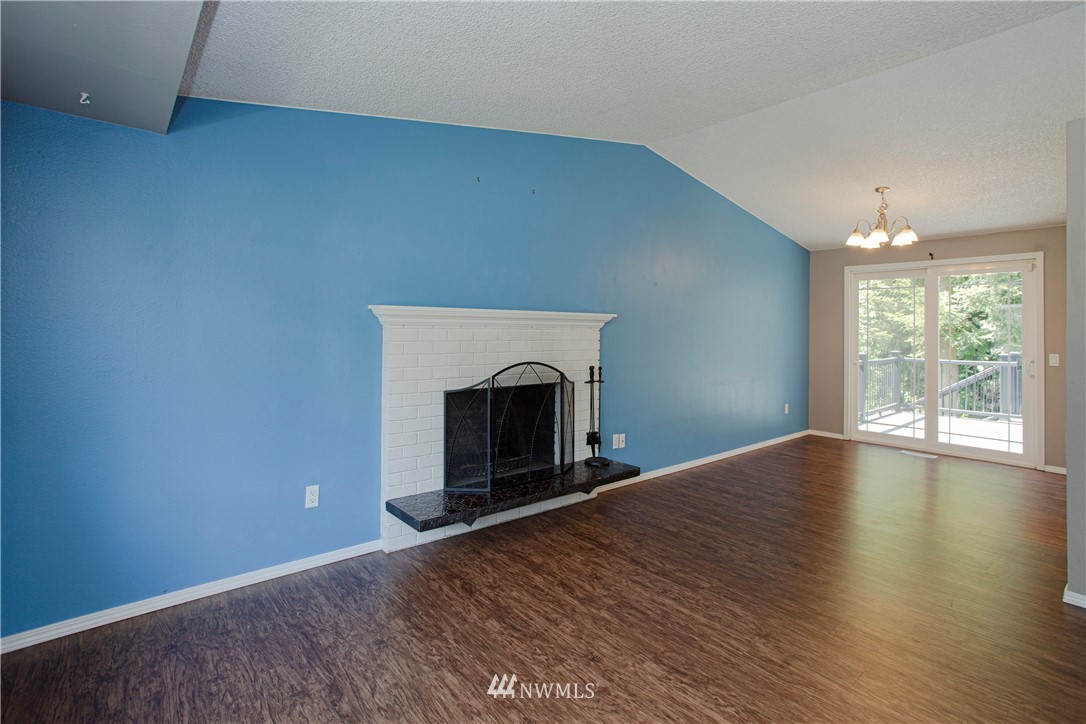 17522 Brook Boulevard Bothell, WA 98012 - Photo 3 of 35 an empty room with wooden floor fireplace and windows