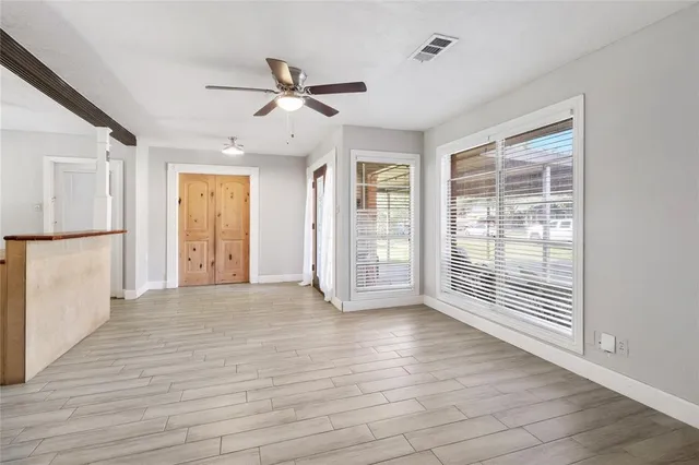 a view of an empty room with a window and wooden floor