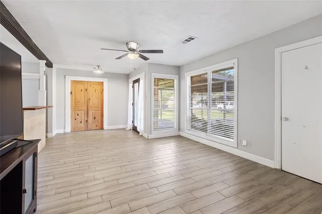 a view of an empty room with a window and wooden floor