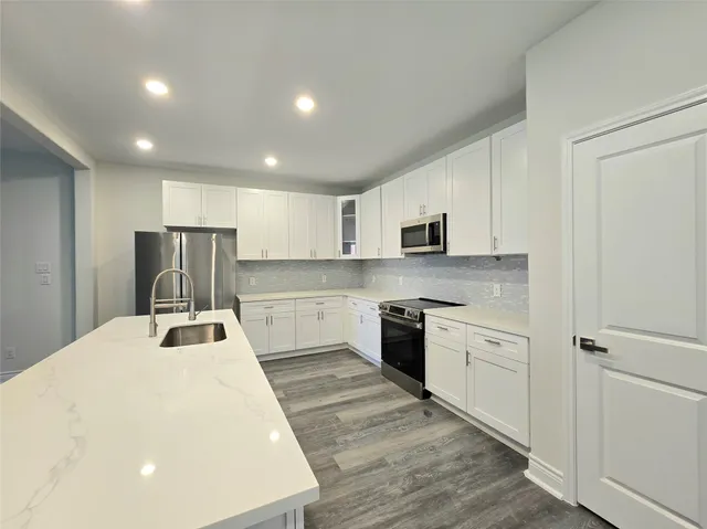 a kitchen with granite countertop a refrigerator stove top oven and sink