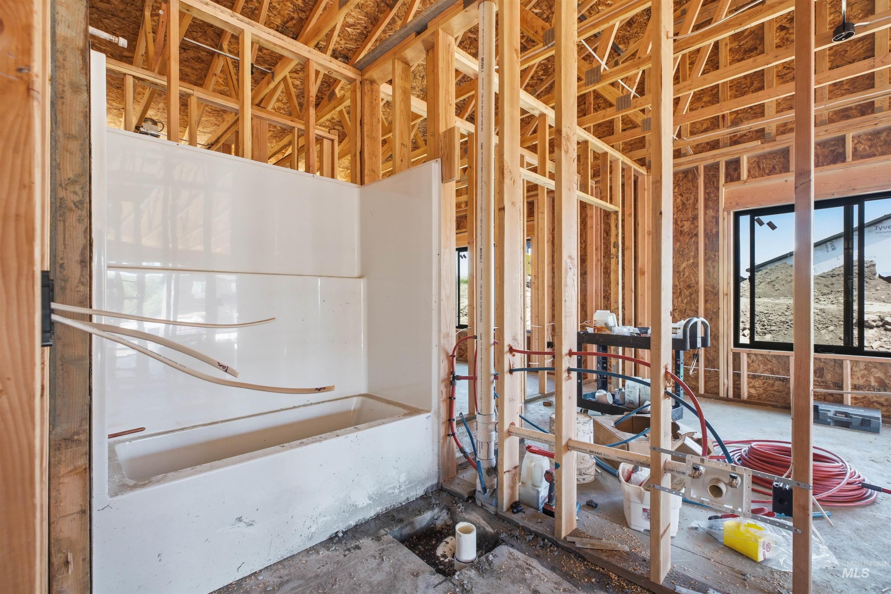 2824 Cyprus Court Moscow, ID 83843 - Photo 13 of 20 Framed interior featuring a white bathtub and shower surround, exposed wood framing, and black-framed windows