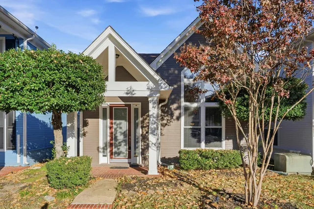 a front view of a house with a tree