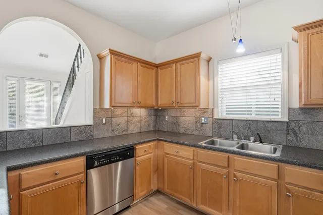 a kitchen with granite countertop a sink a window and cabinets