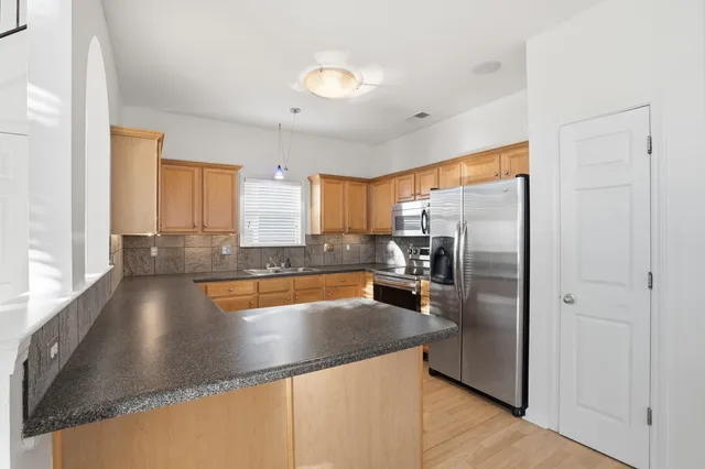 a view of a kitchen with a stove a faucet and a refrigerator with wooden floor