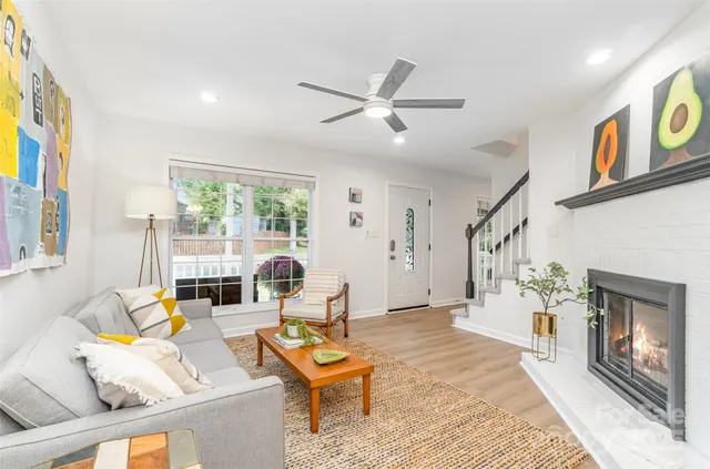 a living room with furniture large window and wooden floor