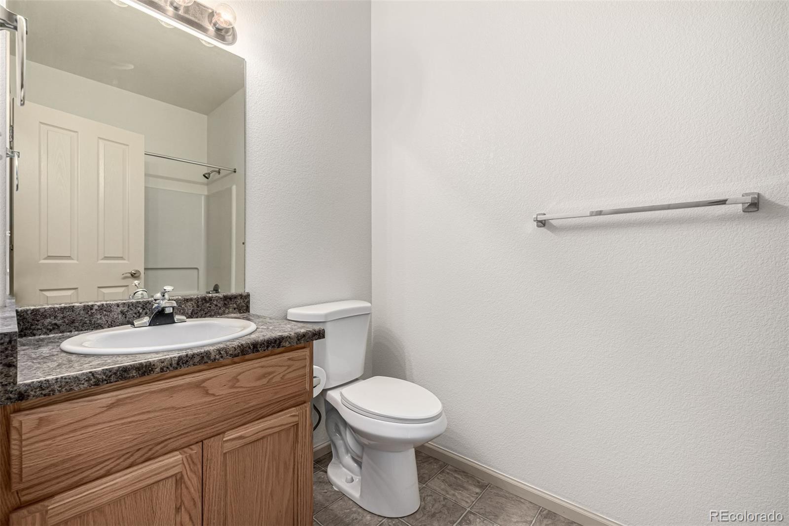 268 Naples Street Firestone, CO 80520 - Photo 22 of 34 a bathroom with a granite countertop toilet a sink and a mirror