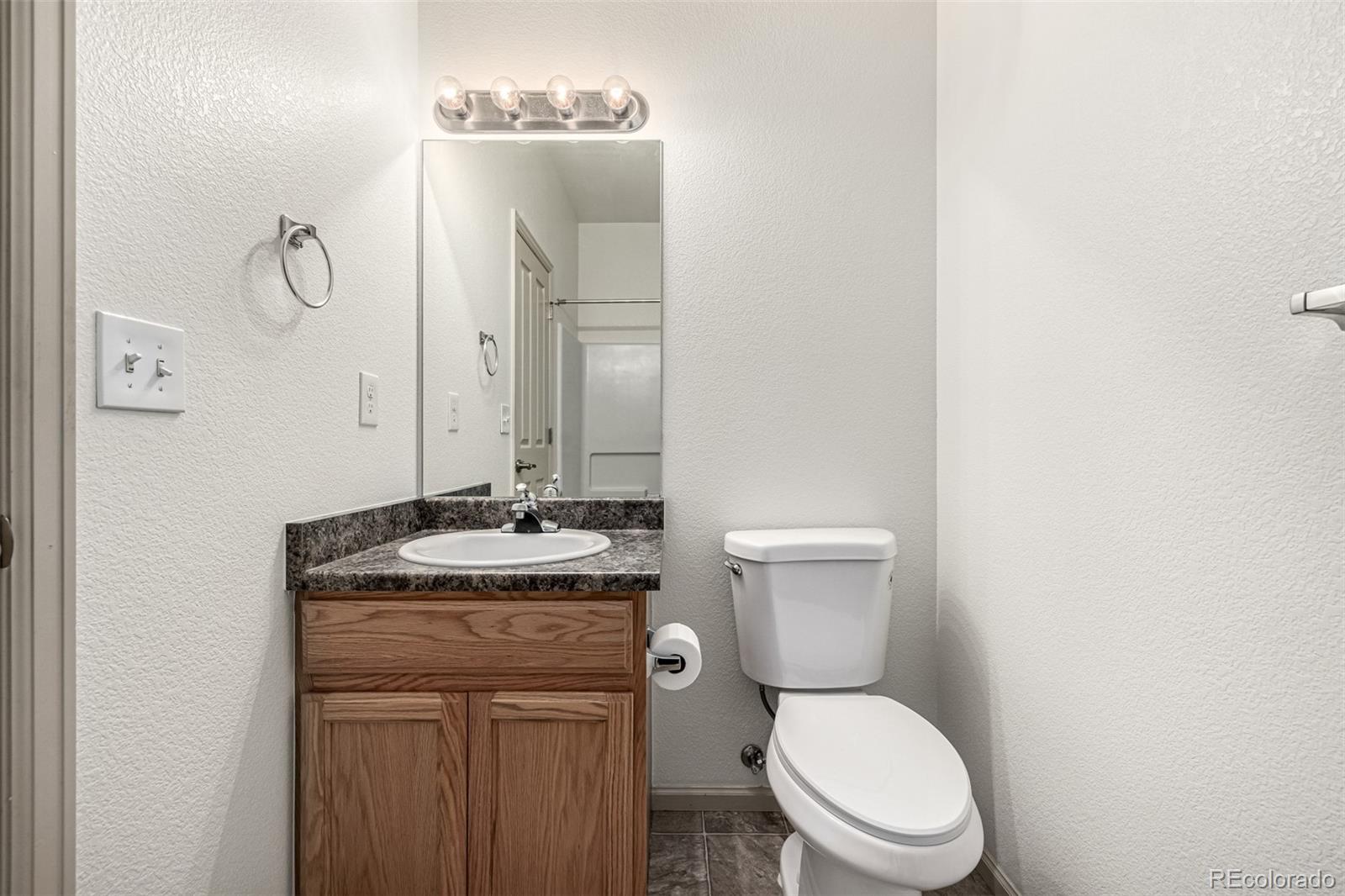 268 Naples Street Firestone, CO 80520 - Photo 23 of 34 a bathroom with a granite countertop toilet sink and mirror