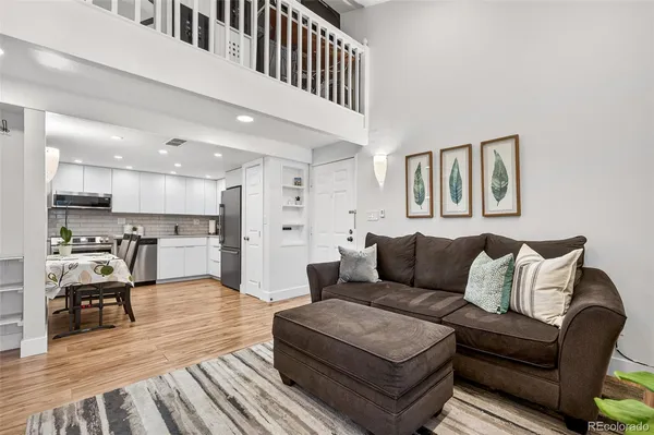 a living room with furniture and kitchen view with wooden floor