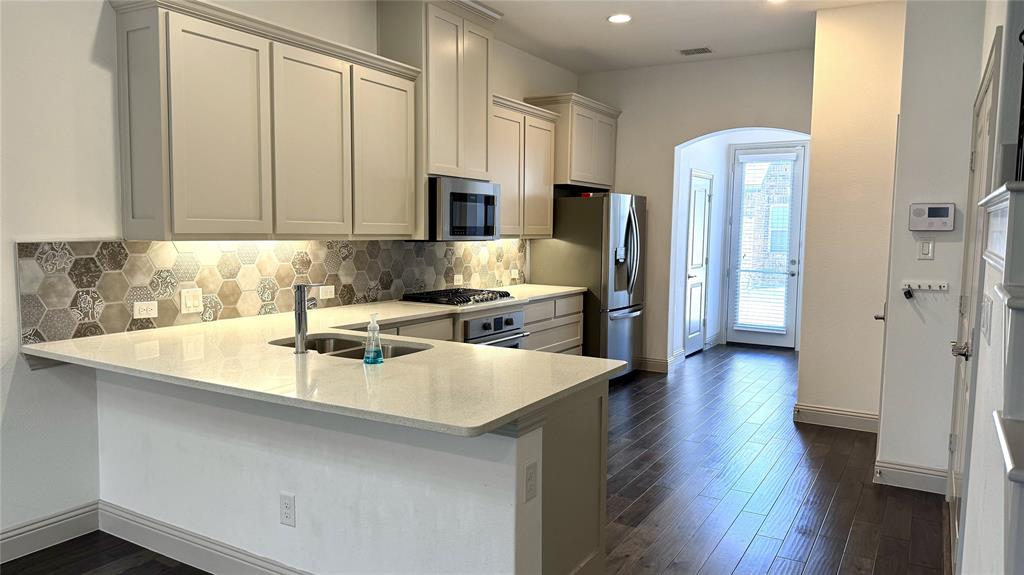 4683 B Rhett Lane Carrollton, TX 75010 - Photo 2 of 21 a kitchen with stainless steel appliances granite countertop a refrigerator a sink a stove and white cabinets with wooden floor