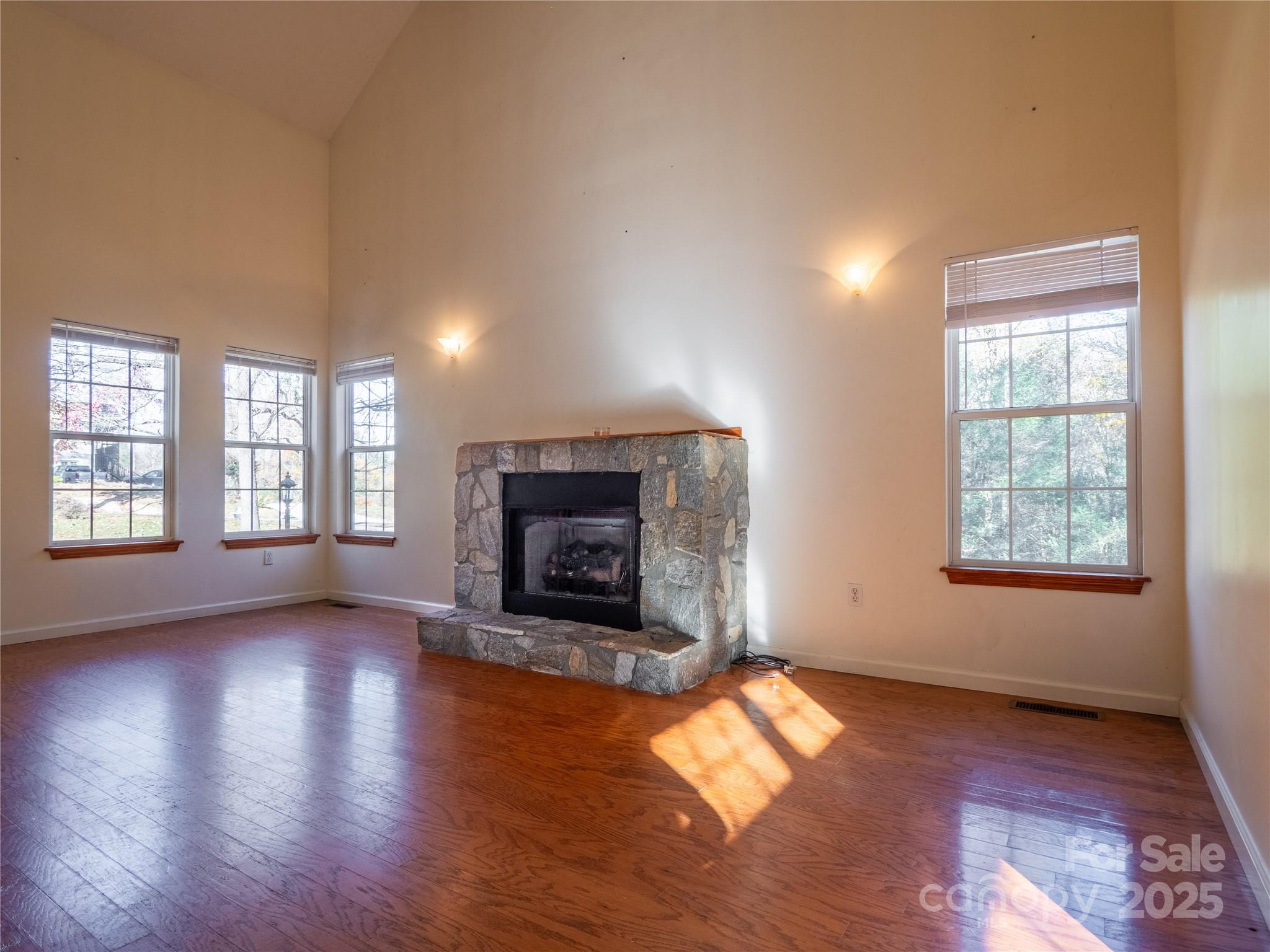 488 Oleta Road Hendersonville, NC 28792 - Photo 3 of 27 an empty room with wooden floor fire place and windows